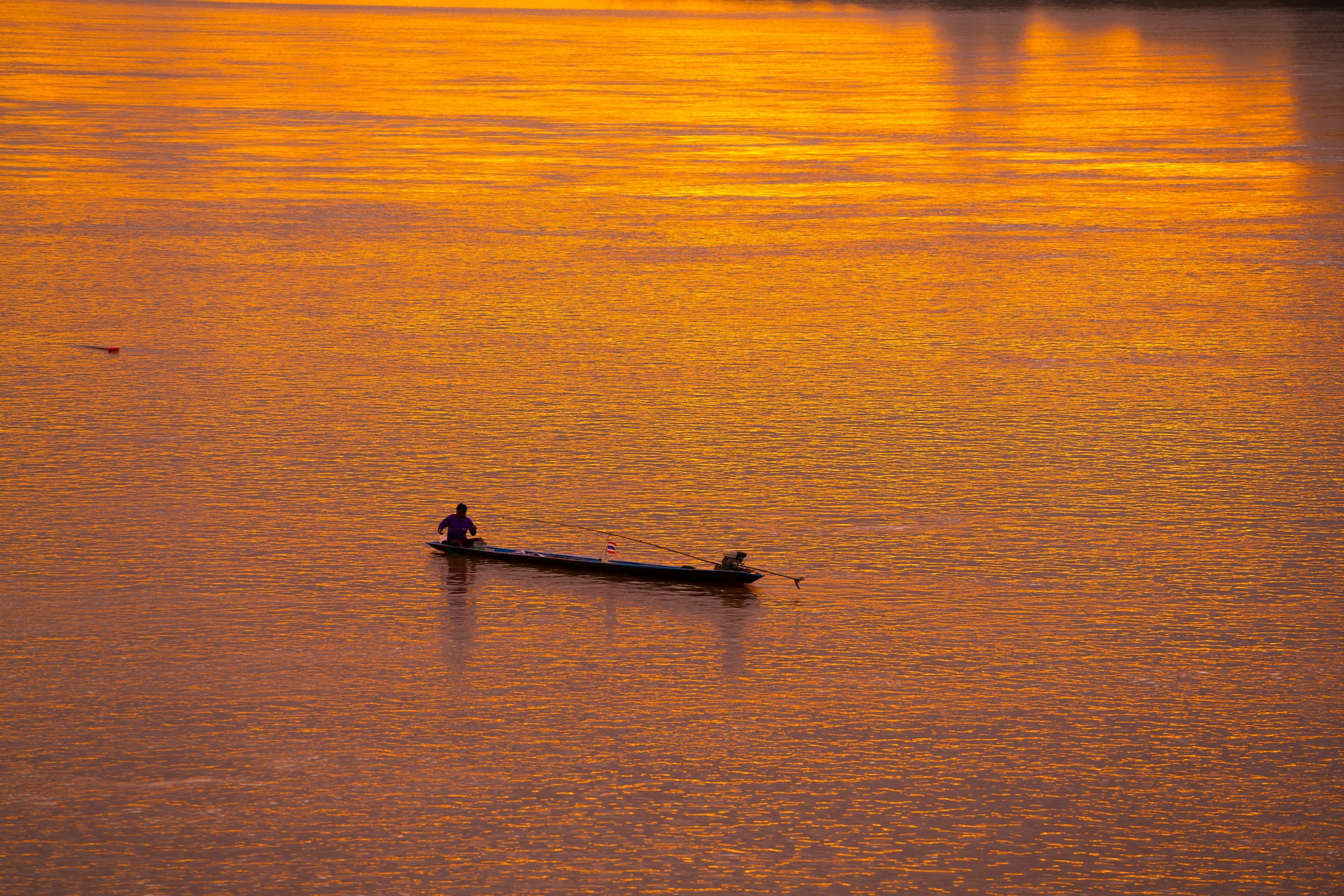 Fishing man on wood boat in lake sunset